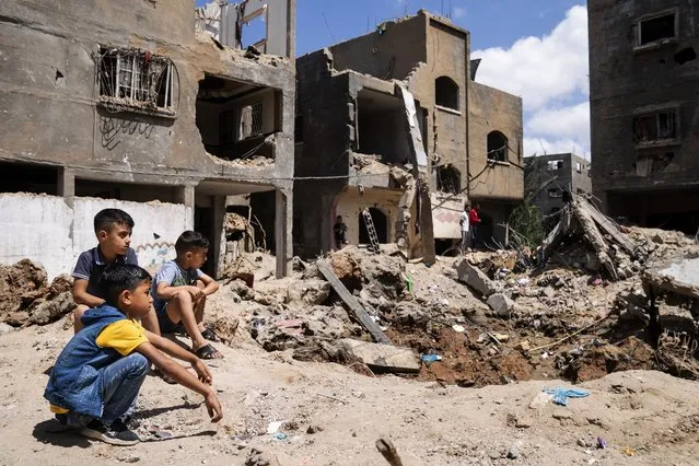 Children gather beside the crater where the home of Ramez al-Masri was destroyed by an air-strike prior to a cease-fire reached after an 11-day war between Gaza's Hamas rulers and Israel, Sunday, May 23, 2021, in Beit Hanoun, the northern Gaza Strip. (Photo by John Minchillo/AP Photo)