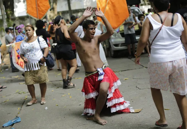 A patient from the Nise de Silveira mental health institute dances in costume during the institute's carnival parade, called in Portuguese: “Loucura Suburbana”, or Suburban Madness, in the streets of Rio de Janeiro, Brazil, Thursday, February 4, 2016. Patients, their relatives and workers from the institute held their parade one day before the official start of Carnival. (Photo by Silvia Izquierdo/AP Photo)