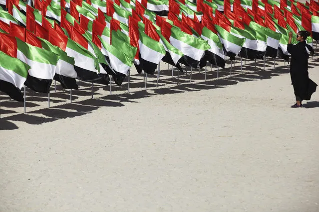 A woman takes a photograph of a display of Emirati flags set up for National Day in Dubai, United Arab Emirates, Sunday, December 2, 2018. The UAE on Sunday celebrated its National Day, which marks the creation of the country in 1971 out of the former Trucial States. (Photo by Jon Gambrell/AP Photo)
