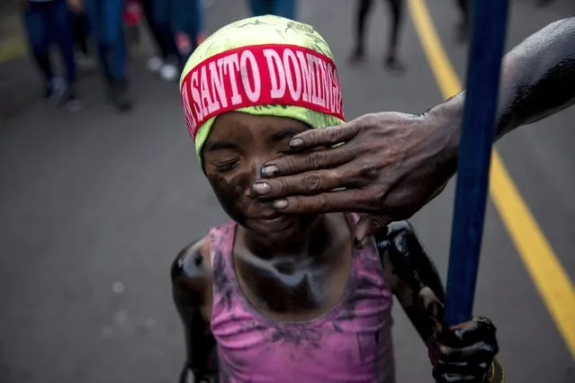 A young girl painted with black oil takes part in the procession in honor of Santo Domingo de Guzman, in Managua, Nicaragua, 01 August 2022. After a three year absence due to the Covid-19 pandemic, the image of Santo Domingo de Guzman returned to rule the festivities in his honor, the largest that is celebrated in Nicaragua. Tens of thousands of faithful Catholics gathered in the southeast of the Nicaraguan capital, to accompany the image of Santo Domingo de Guzman on its annual journey of ten kilometers, from the outskirts to the old center of the city. (Photo by Jorge Torres/EPA/EFE)