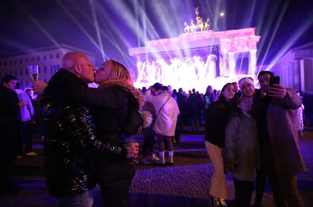 Visitors celebrate the new year at the Brandenburg Gate on January 01, 2023 in Berlin, Germany. For the past two years amidst the Coronavirus (COVID-19) pandemic, there was a national ban on purchasing and setting off fireworks in the country in order to avoid the gathering of crowds thwarting social distancing policies as well as to prevent the overburdening of hospitals. While the ban has been lifted to allow sales and use of fireworks over a period of three days, no official fireworks show as per the annual tradition was held at the Brandenburg Gate. (Photo by Adam Berry/Getty Images)