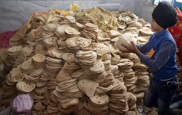 An Indian Sikh volunteer child arranges Chappatis at Langer, holy food kitchen on the occasion of the 350th birth anniversary of the Sikh Guru Sri Guru Gobind Singh, in Jammu the winter capital of Kashmir, India, 05 January 2017. Guru Gobind Singh was the tenth and last of the ten Gurus (masters) of the Sikhs. (Photo by Jaipal Singh/EPA)