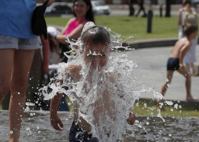 An Ukrainian boy fools around in a fountain on the Independence Square in Kiev, Ukraine, 01 July 2021. According to reports, the temperature reached 33 degrees Celsius in the Ukrainian capital. (Photo by Sergey Dolzhenko/EPA/EFE)