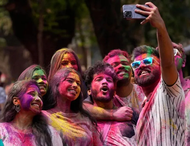 People smeared with colors take selfie during celebrations marking Holi, the Hindu festival of colors, in Mumbai, India, Tuesday, March 7, 2023. The festival heralds the arrival of spring. (Photo by Rajanish Kakade/AP Photo)