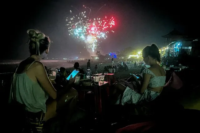 Fireworks illuminate the night sky as revelers celebrate New Year's Eve at the beach on December 31, 2023 in the Kerobokan district on the resort island of Bali, Indonesia. (Photo by David Gannon/AFP Photo)