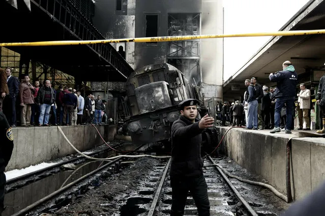 Policemen stand guard in front of a damaged train inside Ramsis train station in Cairo, Egypt, Wednesday, February 27, 2019. An Egyptian medical official said at least 20 people have been killed and dozens injured after a railcar rammed into a barrier inside the station causing an explosion of the fuel tank and triggering a huge blaze that engulfed that part of the station. The head of the Cairo Railroad Hospital said the death toll is expected to rise further. (Photo by Nariman El-Mofty/AP Photo)