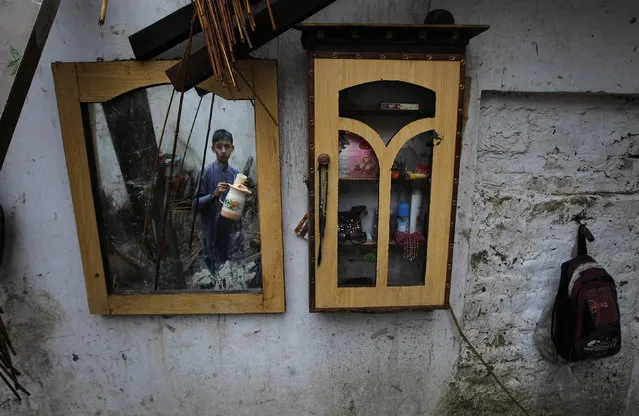 A Pakistani boy collects his belongings from his home that was damaged from heavy rain and windstorm that reached up to a speed of 120 kph (75 mph) Sunday evening which collapsed hundreds of buildings, uprooted trees, and electric poles, in Peshawar, Pakistan, Monday, April 27, 2015. (Photo by Mohammad Sajjad/AP Photo)