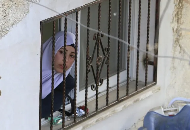 A Palestinian woman looks out of her window as she watches the funeral of Palestinian Ahmad Aamer, 16, who the Israeli military said was shot dead by Israeli soldiers after he tried to stab them, in the West Bank village of Mas'ha near Salfit March 9, 2016. (Photo by Abed Omar Qusini/Reuters)