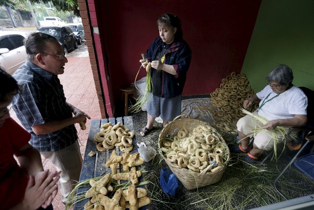 Pedro Antar (2nd L) and Celia (R) prepare traditional cheese and corn buns called “chipas”, in celebration of Kurusu Ara in Asuncion May 3, 2015. (Photo by Jorge Adorno/Reuters)