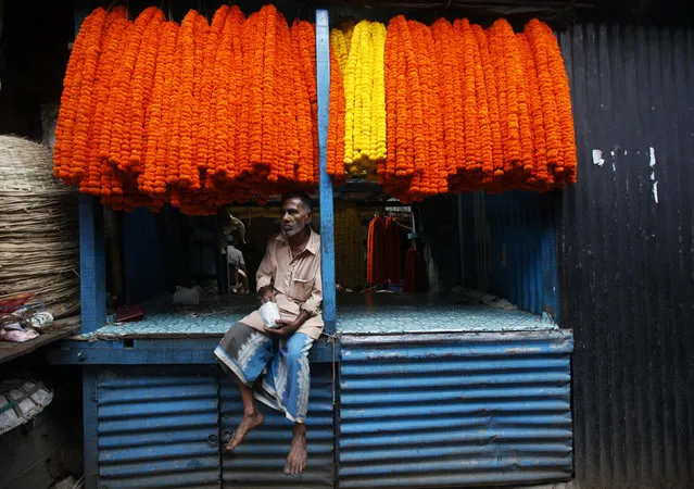 A vendor selling garlands of marigold flowers eats as he waits for customers at a wholesale flower market ahead of Durga Puja festival in Kolkata October 9, 2013. (Photo by Rupak De Chowdhuri/Reuters)