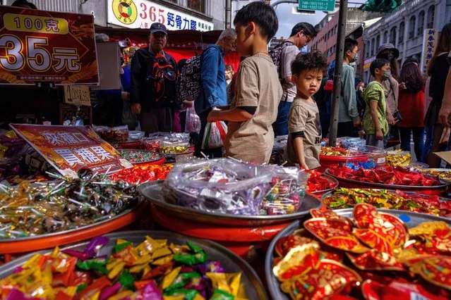 Children stand at a candy stall on Dihua Street, which is the most popular grocery market for shopping Chinese New Year's goods on February 03, 2024 in Taipei, Taiwan. Lunar New Year is the beginning of the new year based on the lunar calendar. It is one of the most important holidays in Chinese culture. Members of the family sit around a big table to have a Chinese New Year's Eve dinner together, which will be on February 9 this year. (Photo by Annabelle Chih/Getty Images)
