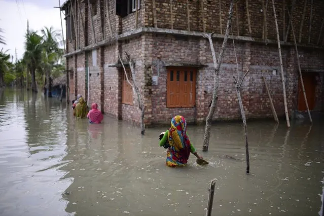 Villagers wade through waist-deep waters to reach their homes in Pratap Nagar that lies in the Shyamnagar region, in Satkhira, Bangladesh on October 5, 2021. (Photo by Mahmud Hossain Opu/AP Photo)