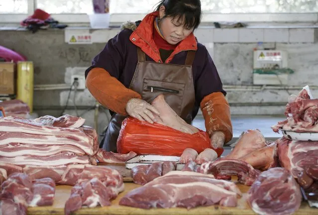 A pork butcher packs a pig's head at a market in Beijing, China, March 25, 2016. An exodus of small pig farmers in China is prolonging an industry downturn that will see the world's biggest pork producer and consumer challenge Japan as the top importer in 2016 for the first time. (Photo by Jason Lee/Reuters)