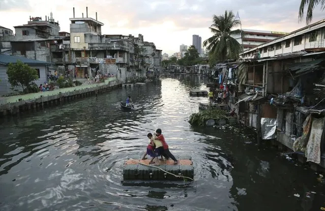 Filipino boys play on floaters beside their creekside homes in Manila, Philippines Wednesday, March 30, 2016. The government continues to clear garbage and shanties along the creeks to avoid floodings in parts of the city. (Photo by Aaron Favila/AP Photo)