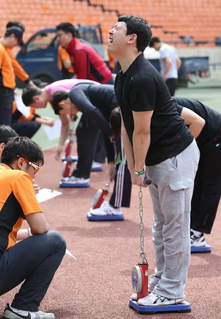 An examiner tests a prospective firefighter's back muscle strength during a firefighter physical ability exam at Jamsil Stadium in Seoul, South Korea, 11 May 2015. (Photo by EPA/Yonhap)