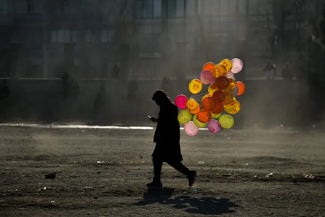 An Afghan hawker selling balloons walks along a path in a ground in Chaman-e-Hozori area in Kabul on December 10, 2021. (Photo by Ahmad Sahel Arman/AFP Photo)