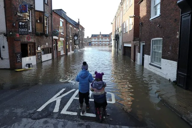Two children stand on a partially flooded street after the River Ouse burst banks in York, Britain, January 22, 2021. (Photo by Lee Smith/Reuters)