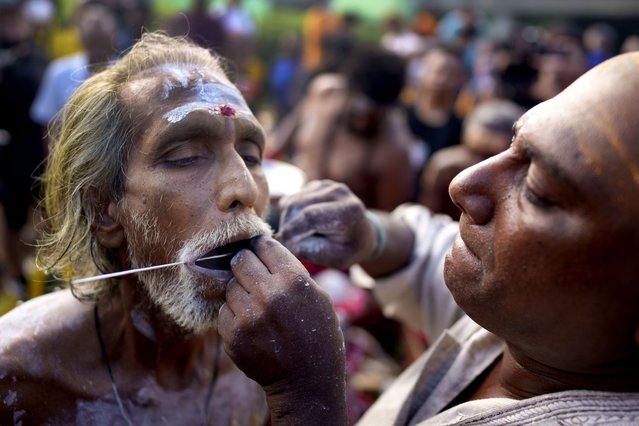 A Hindu devotee gets his tongue pierced with a metal rod during the Thaipusam festival celebrations at Batu Caves, Kuala Lumpur, Malaysia Thursday, January 25, 2024. Thaipusam, which is celebrated in honor of Hindu god Lord Murugan, is an annual procession by Hindu devotees seeking blessings, fulfilling vows and offering thanks. (Photo by Vincent Thian/AP Photo)