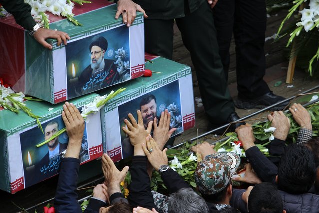 In this photo provided by Fars News Agency, mourners try to touch the coffins of Iranian President Ebrahim Raisi, top, Foreign Minister Hossein Amirabdollahian, left, and Raisi's chief bodyguard Gen. Mehdi Mousavi, who were killed in a helicopter crash on Sunday in a mountainous region of the country's northwest, during a funeral ceremony at the city of Tabriz, Iran, Tuesday, May 21, 2024. Mourners in black began gathering Tuesday for days of funerals and processions for Iran's late president, foreign minister and others killed in a helicopter crash, a government-led series of ceremonies aimed at both honoring the dead and projecting strength in an unsettled Middle East. (Photo by Ata Dadashi, Fars News Agency via AP Photo)