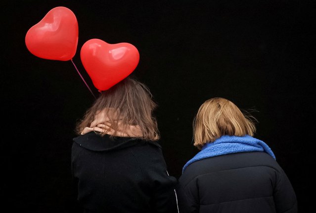 Women with Valentine's Day balloons walk along a street, amid Russia's attack on Ukraine, in central Kyiv, Ukraine on February 14, 2023. (Photo by Gleb Garanich/Reuters)