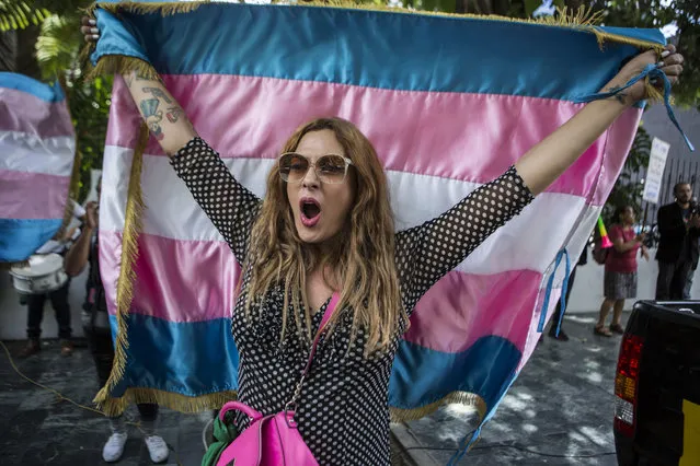 Lola Vazquez, who identifies as transgender, waves a transgender flag during a protest against a deal Guatemalan President Jimmy Morales' government signed with Washington that would force Salvadoran and Honduran migrants to request asylum in Guatemala instead of the United States, in Guatemala City, Wednesday, July 31, 2019. Critics of the deal point out that Guatemala has the same problems that are driving Hondurans and Salvadorans to flee their homes: violence, poverty, joblessness and a prolonged drought that has severely hurt farmers. (Photo by Oliver de Ros/AP Photo)