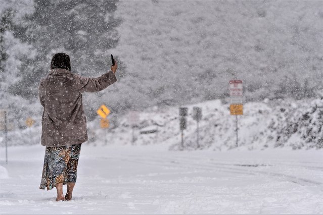 A visitor stands on a snow-covered road while taking a selfie in the Angeles National Forest near La Canada Flintridge, Calif., Thursday, February 23, 2023. (Photo by Jae C. Hong/AP Photo)