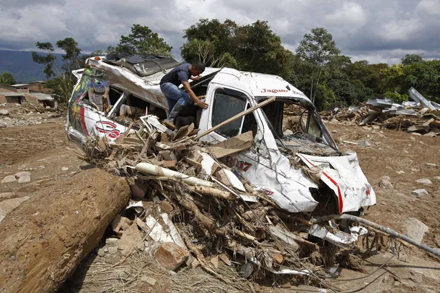 A man looks inside a damage passenger bus in Mocoa, Colombia, Sunday, April 2, 2017. Colombia's President Juan Manuel Santos, who has declared Mocoa a disaster area, said that at least 207 were killed but that the death toll was changing “every moment”. Authorities said another 200 people, many of them children, were injured and just as many were unaccounted for amid the destruction. (Photo by Fernando Vergara/AP Photo)