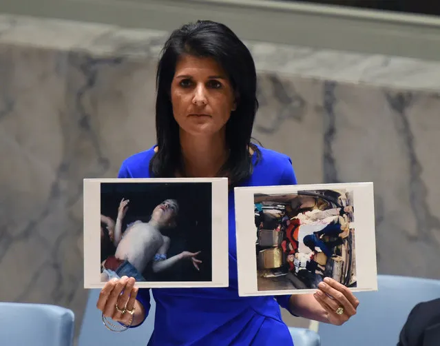 US Ambassador to the UN, Nikki Haley holds photos of victims as she speaks as the UN Security Council meets in an emergency session at the UN on April 5, 2017, about the suspected deadly chemical attack that killed civilians, including children, in Syria. (Photo by Timothy A. Clary/AFP Photo)