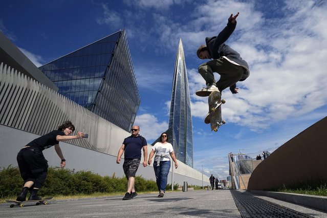A boy jumps with a skateboard near the Lakhta Center skyscraper, the headquarters of Russian gas monopoly Gazprom in St. Petersburg, Russia, Wednesday, June 12, 2024. (Photo by Dmitri Lovetsky/AP Photo)