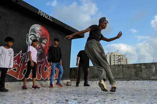 In this picture taken on July 02, 2021 a student perform during a group class to learn breaking or “b-boying” at a training session on the rooftop of a building in Dharavi slums in Mumbai. After India's largest slum defeated the pandemic, some of its young residents pulled out their phones to write, shoot and release a triumphant rap video. (Photo by Punit Paranjpe/AFP Photo)