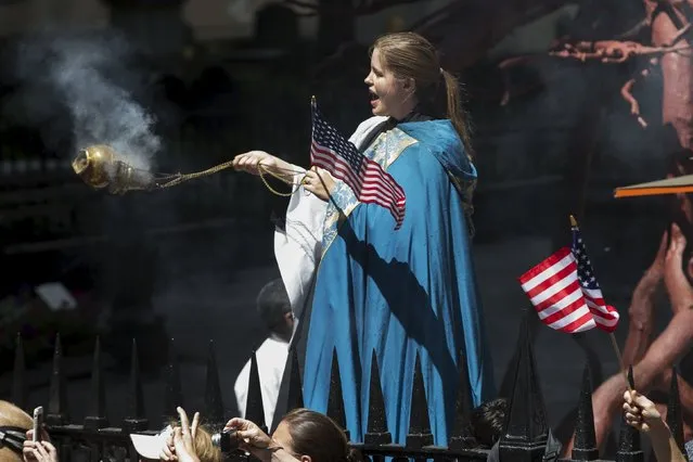 A clergy member spreads incense as she stands outside Trinity Church as the U.S. women's soccer team passes in floats during the ticker tape parade up Broadway in lower Manhattan to celebrate their World Cup final win over Japan in New York, July 10, 2015. (Photo by Mike Segar/Reuters)