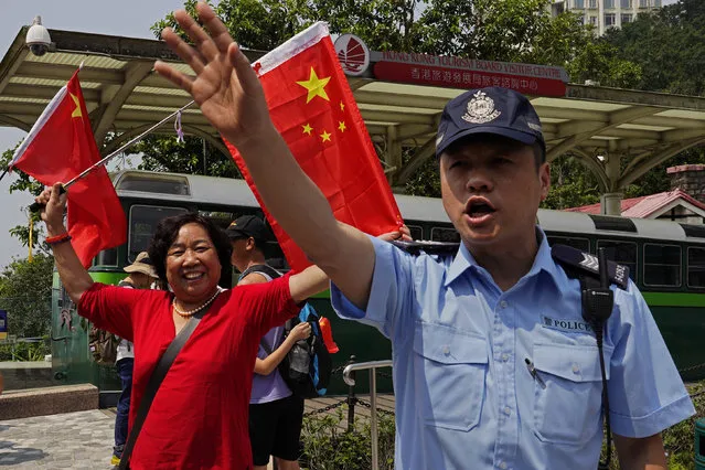 A police officer tries to keep the pro-China supporters in order at the Peak in Hong Kong Sunday, September 29, 2019. Hundreds of pro-Beijing supporters sang Chinese national anthem and waved red flags ahead of China's National Day, in a counter to months-long pro-democracy protests viewed as a challenge to Beijing's rule. (Photo by Vincent Yu/AP Photo)