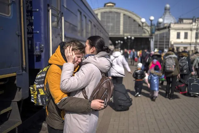 A mother embraces her son who escaped the besieged city of Mariupol and arrived at the train station in Lviv, western Ukraine on Sunday, March 20, 2022. (Photo by Bernat Armangue/AP Photo)