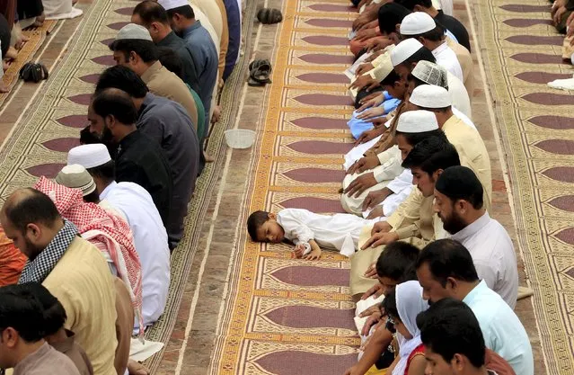 A boy lies in front of his father as he offer last Friday prayers of the holy fasting month of Ramadan with others at the Jama Masjid (Grand Mosque) in Rawalpindi, Pakistan, July 17, 2015. (Photo by Faisal Mahmood/Reuters)