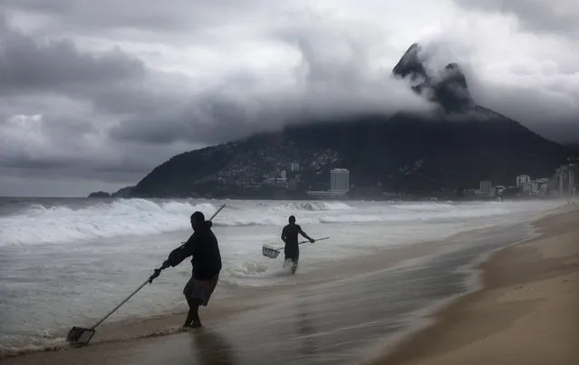 Freelance beach prospector Luis Fernando (L) manuevers a sifting device which he uses to search for items lost and buried in the sand on June 21, 2017 in Rio de Janeiro, Brazil. He says he discovers lost coins, jewelry, cell phones, and a host of other items. He said on an average day he will earn about $12 USD and on a “lucky” day he could find valuables worth up to $300 USD. Today marked the first day of winter in Brazil and the rest of the Southern Hemisphere. (Photo by Mario Tama/Getty Images)