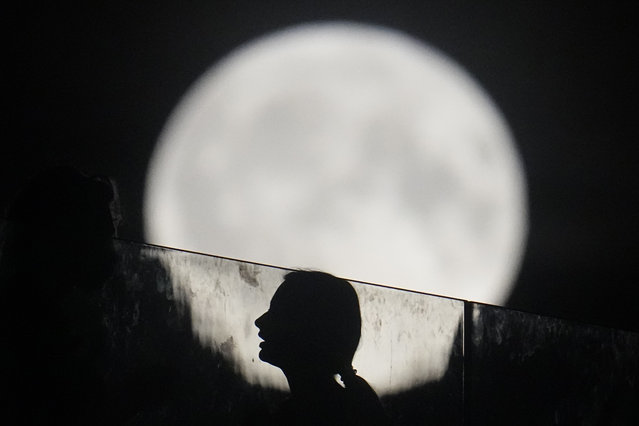 A woman stands on a floating bridge while the supermoon rises in Moscow, August 19, 2024. (Photo by Pavel Bednyakov/AP Photo)