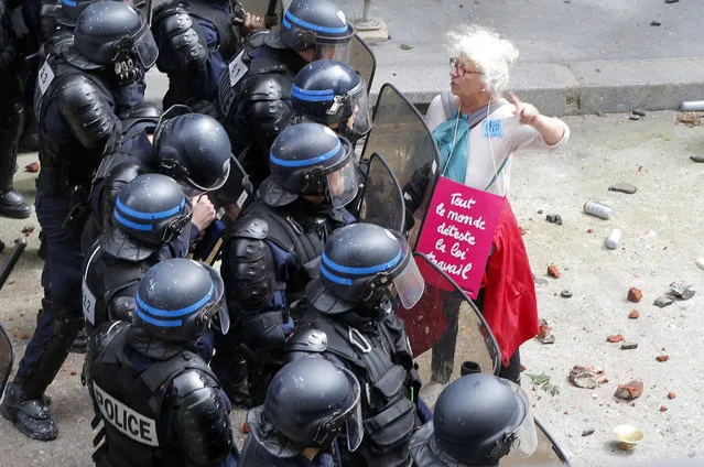 A woman, with a poster reading “We all hate the Labor Law”, argues with riot police officers during a demonstration in Paris Tuesday, June 14, 2016. Protesters in Paris threw projectiles at police officers, who responded with tear gas, amid demonstrations by tens of thousands of people opposed to a proposed labor law. (Photo by Francois Mori/AP Photo)