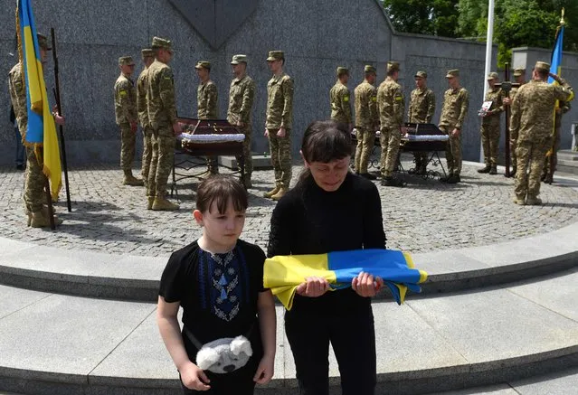 Widow and daughter of Andriy Vertiev, a Ukrainian serviceman, killed during the Russian invasion of Ukraine, react during the funeral at Lychakiv cemetery in the western Ukrainian city of Lviv, on May 25, 2022. (Photo by Yuriy Dyachyshyn/AFP Photo)