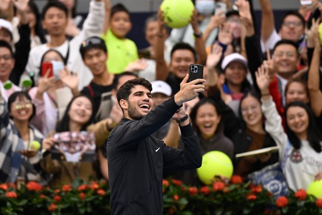 Spain's Carlos Alcaraz takes photos with fans after winning against France's Giovanni Mpetshi Perricard during their men's singles match at the China Open tournament in Beijing on September 27, 2024. (Photo by Wang Zhao/AFP Photo)