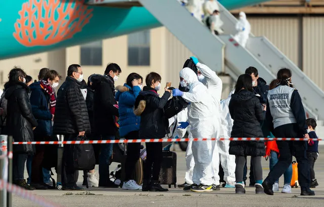 This handout photo taken and released by the French Defence Audiovisual Production and Communication Unit (ECPAD) on February 2, 2020, shows passengers being checked as they disembark from a plane carrying French citizens flown out of the coronavirus hot-zone in Wuhan, upon their arrival at the Istres-Le Tube Air Base in Istres, southeastern France. At least 65 more French citizens began a quarantine period in southern France on February 2, after a second repatriation plane landed in Istres carrying overall 250 people from Wuhan, the epicentre of the new coronavirus infection epidemic. (Photo by Handout/ECPAD/AFP Photo)