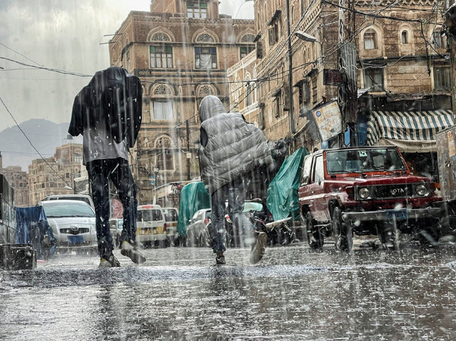 People walk during a rainfall in the old quarter of Sanaa, Yemen on June 25, 2022. (Photo by Khaled Abdullah/Reuters)