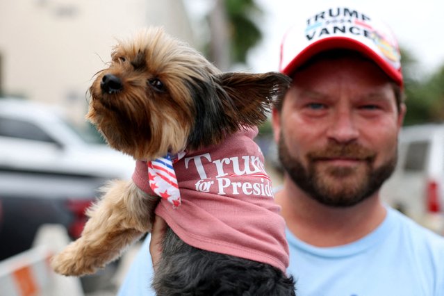 A man holds up his dog near the Morton and Barbara Mandel Recreation Center, where Republican presidential nominee and former President Donald Trump and former first lady Melania Trump were expected to vote, in Palm Beach, Florida, on Election Day on November 5, 2024. (Photo by Ricardo Arduengo/Reuters)