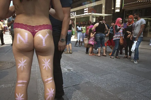 A woman who poses for tips wearing body paint and underwear collects a tip from a man who posed for a photo with her in Times Square in New York, August 18, 2015. (Photo by Carlo Allegri/Reuters)