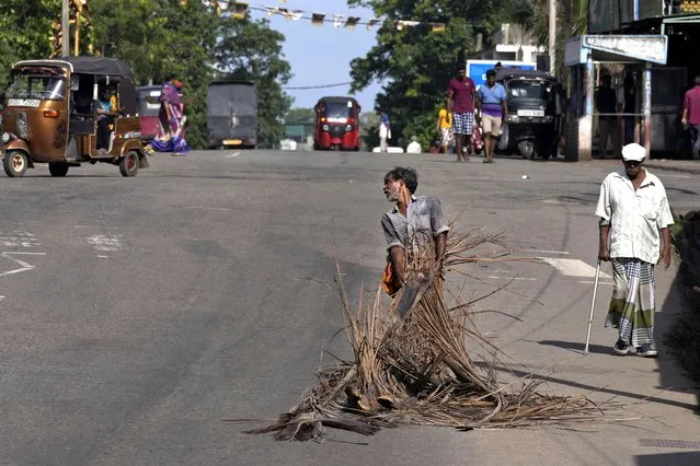 A man pulls fallen coconut leaves to be used as firewood amid shortage of cooking gas along a usually congested road in Colombo, Sri Lanka, Thursday, June 23, 2022. (Photo by Eranga Jayawardena/AP Photo)