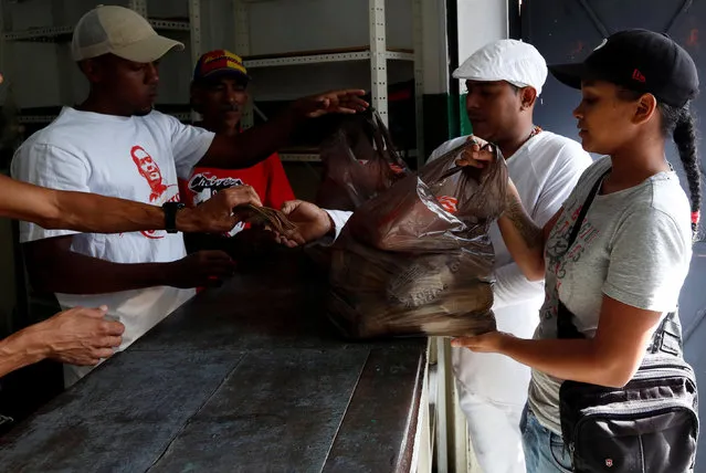 Volunteers sell bags of food to residents under a new government system in providing basic food at low cost, in Caracas, Venezuela July 9, 2016. (Photo by Carlos Jasso/Reuters)