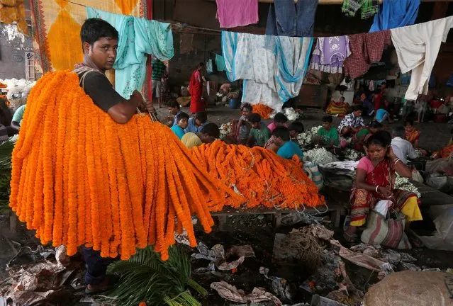 A man carries garlands of marigolds at a wholesale flower market in Kolkata, India July 8, 2016. (Photo by Rupak De Chowdhuri/Reuters)