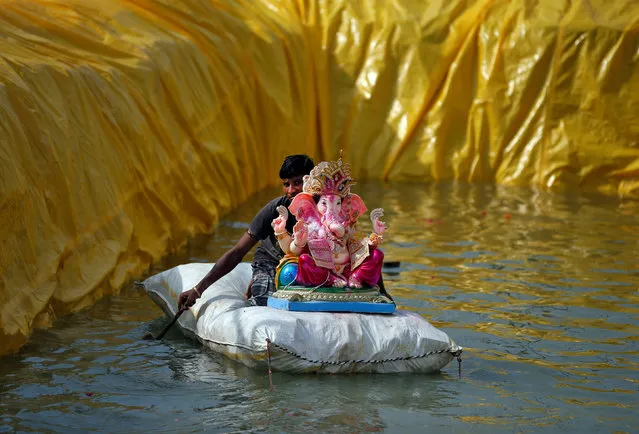 A man transports an idol of the Hindu god Ganesh, the deity of prosperity, on a makeshift raft after it was immersed in a pond on the second day of the ten-day long Ganesh Chaturthi festival in Ahmedabad, India, August 26, 2017. (Photo by Amit Dave/Reuters)