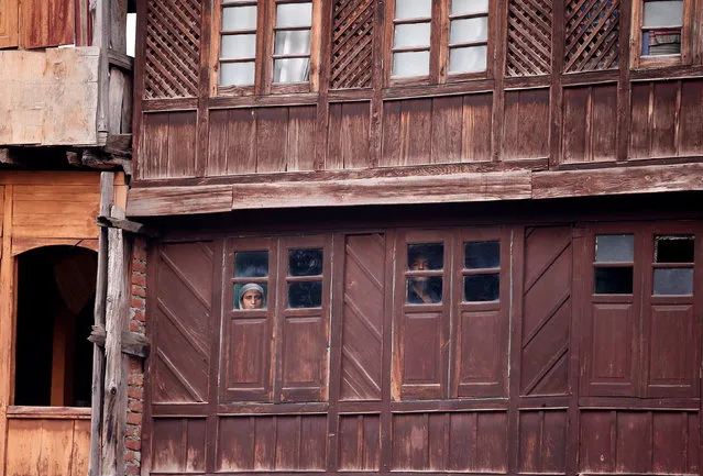 People look out of the windows of a house as Indian police (unseen) attend an event at the Martyrs Graveyard to mark “Martyrs Day” in Srinagar July 13, 2016. On July 13, 1931, dozens of Kashmiris were gunned down by police during a protest against the Hindu Maharaja Hari Singh, then ruler of the Himalayan region. The Kashmir state government also observes the day as Martyrs Day and has declared July 13 a holiday. (Photo by Danish Ismail/Reuters)