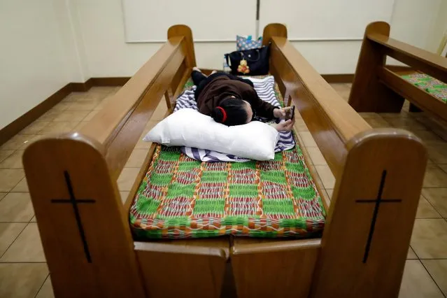 A hospital worker wearing a protective mask rests on a cushion placed on top of pews as a funeral chapel temporarily shelters health workers from a nearby hospital taking in COVID-19 patients, in Makati City, Metro Manila, Philippines, April 1, 2020. (Photo by Eloisa Lopez/Reuters)