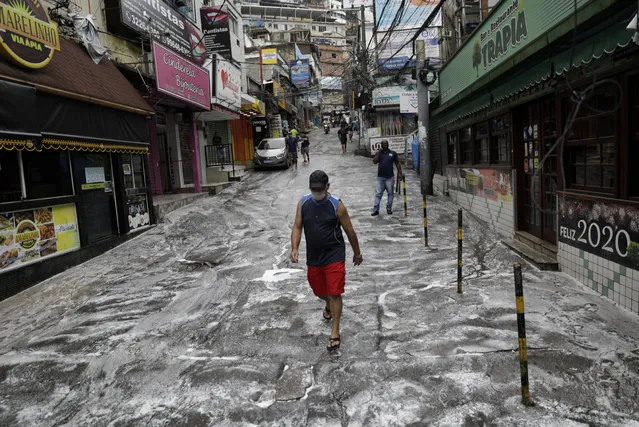 A man wearing a protective mask walks on a street disinfected by cleaners during the coronavirus disease (COVID-19) outbreak, at the Rocinha slum in Rio de Janeiro, Brazil on April 10, 2020. (Photo by Ricardo Moraes/Reuters)